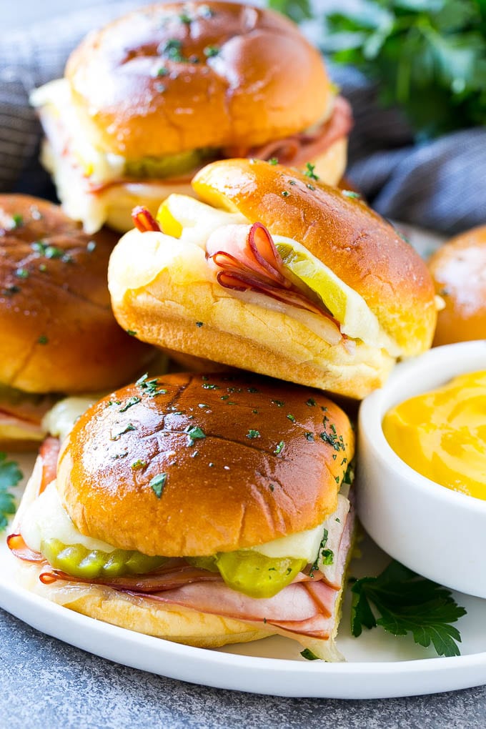 Cuban Sliders Recipe | Cuban Sandwich Recipe | Slider Sandwiches | Ham and Cheese Sliders #sliders #sandwiches #ham #cheese #appetizer #ezlod A plate full of Cuban sliders with cheese, pickles and ham on buns.