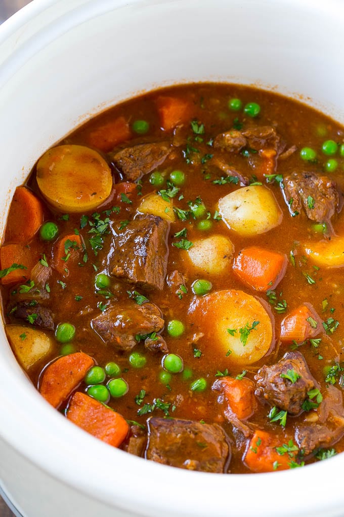 Slow Cooker Beef Stew Recipe | Beef and Potato Stew | Crock Pot Beef Stew | Easy Beef Stew #beef #beefstew #soup #slowcooker #crockpot #dinner #ezlod A slow cooker full of beef stew that contains meat, potatoes, carrots and peas, all in a savory broth.