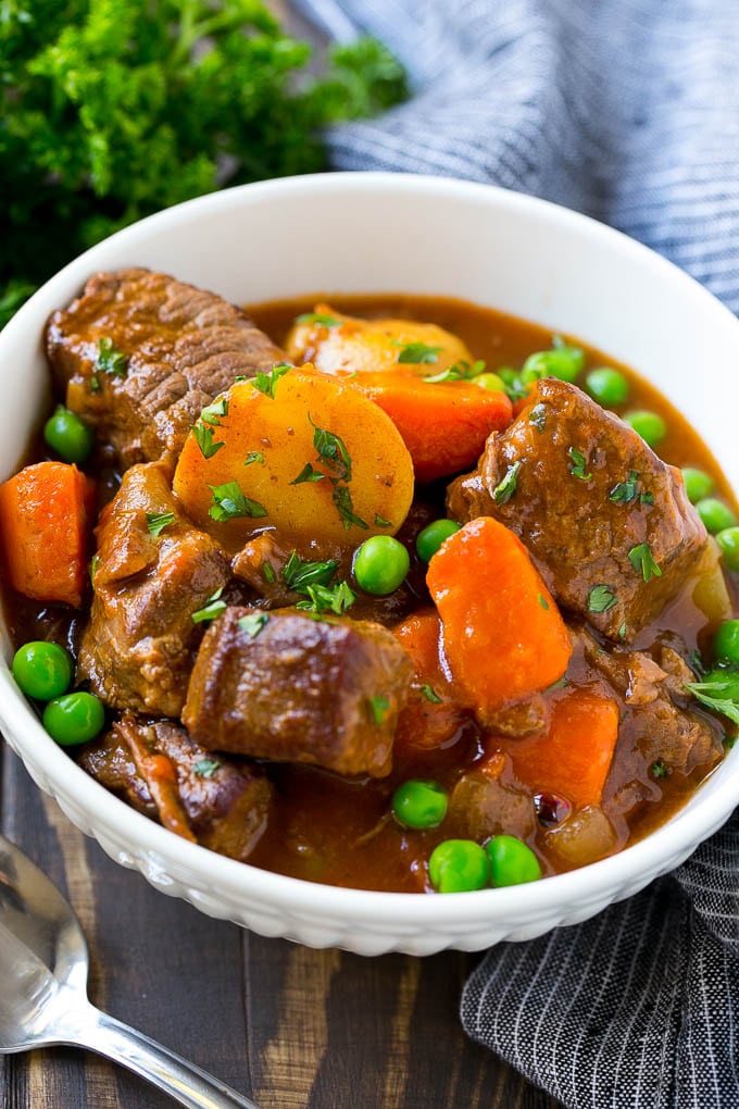 Slow Cooker Beef Stew Recipe | Beef and Potato Stew | Crock Pot Beef Stew | Easy Beef Stew #beef #beefstew #soup #slowcooker #crockpot #dinner #ezlod A bowl of slow cooker beef stew with meat, carrots, potatoes and peas.