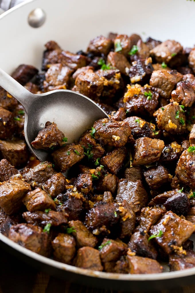 Steak Bites in Garlic Butter Recipe | Garlic Steak | Sirloin Steak Recipe | Steak Appetizer #steak #lowcarb #keto #ezlod #dinner A pan of steak bites with a serving spoon.