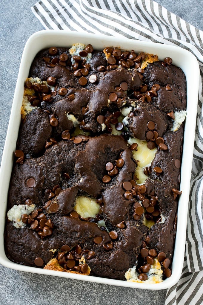 Earthquake Cake Recipe | Chocolate Cake Recipe | Chocolate Coconut Cake | Coconut Pecan Cake #cake #chocolate #coconut #pecans #dessert #chocolatecake #ezlod A pan of earthquake cake topped with dollops of cream cheese and chocolate chips.
