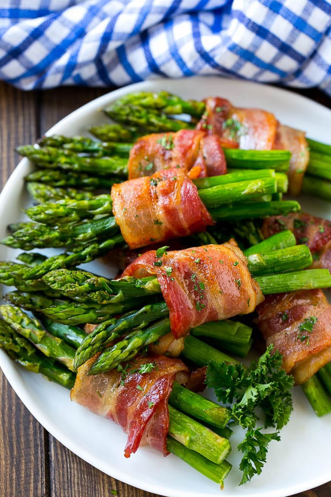 Bacon Wrapped Asparagus Recipe | Roasted Asparagus | Asparagus Side Dish #asparagus #bacon #sidedish #dinner #ezlod A plate of bacon wrapped asparagus bundles garnished with parsley.