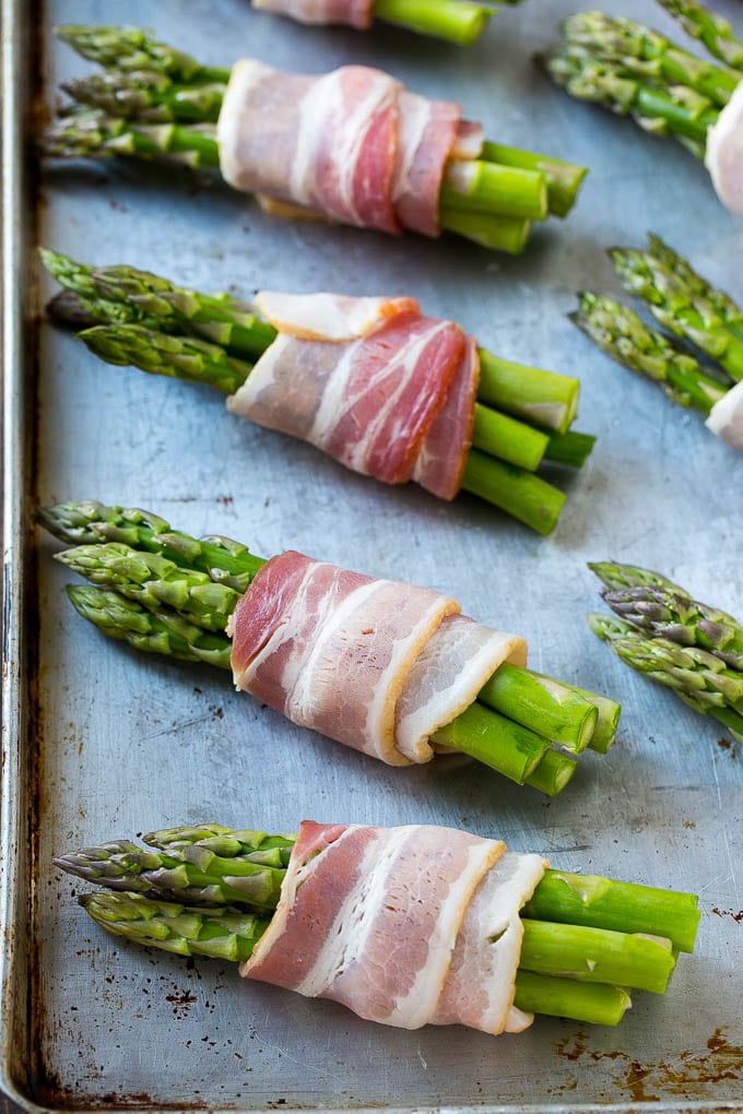 Bacon Wrapped Asparagus Recipe | Roasted Asparagus | Asparagus Side Dish #asparagus #bacon #sidedish #dinner #ezlod Raw asparagus bundles on a sheet pan.