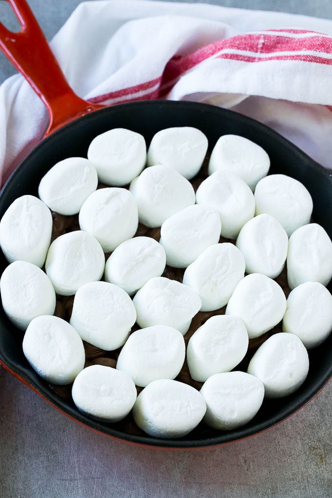 S'mores Dip Recipe | S'mores Skillet | Baked S'mores #smores #dip #chocolate #marshmallow #dessert #ezlod A pan of chocolate chips topped with whole marshmallows.