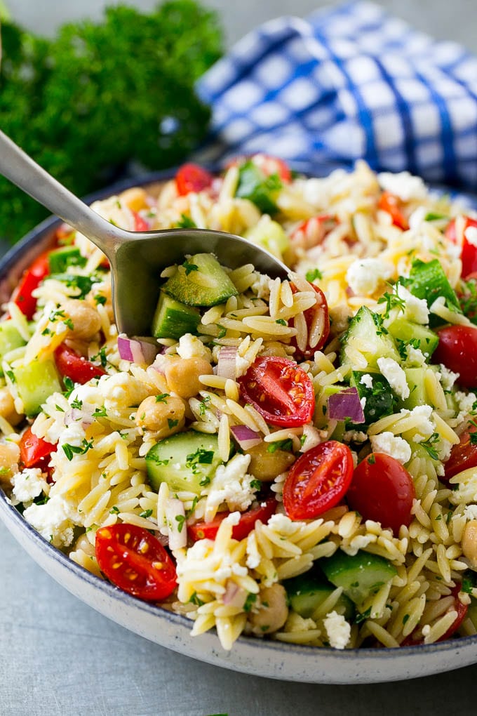 Orzo Salad Recipe | Orzo Pasta Salad | Greek Orzo Salad | Mediterranean Orzo Salad #pastasalad #orzo #greekfood #salad #ezlod Orzo pasta salad with a serving spoon in the bowl.
