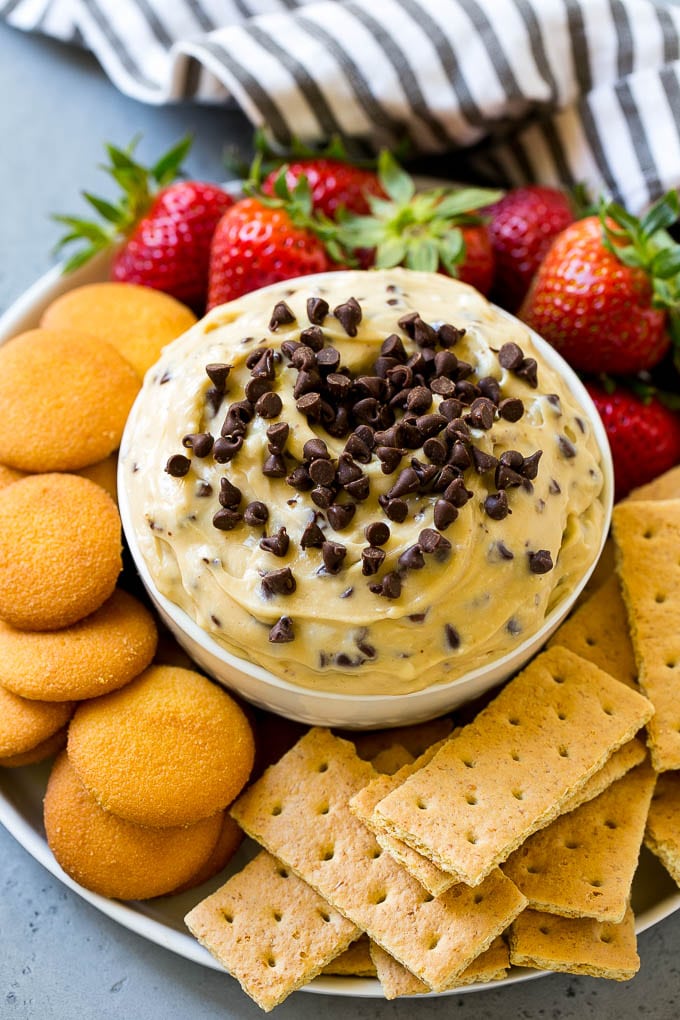 Cookie Dough Dip Recipe | Edible Cookie Dough | Chocolate Chip Cookie Dip #cookies #dip #cookiedough #dessert #snack #ezlod A bowl of cookie dough dip topped with chocolate chips and served with cookies and fruit for dipping.