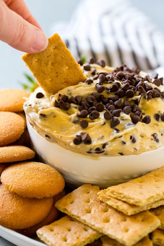 Cookie Dough Dip Recipe | Edible Cookie Dough | Chocolate Chip Cookie Dip #cookies #dip #cookiedough #dessert #snack #ezlod A graham cracker dipping into a bowl of cookie dough dip.