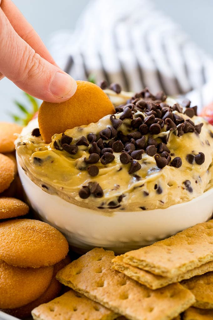 Cookie Dough Dip Recipe | Edible Cookie Dough | Chocolate Chip Cookie Dip #cookies #dip #cookiedough #dessert #snack #ezlod A cookie scooping into a bowl of dip.