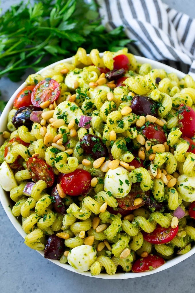 Pesto Pasta Salad | Italian Pasta Salad | Easy Pasta Salad #pasta #salad #pesto #olives #tomatoes #ezlod A bowl of pesto pasta salad topped with pine nuts and chopped parsley.