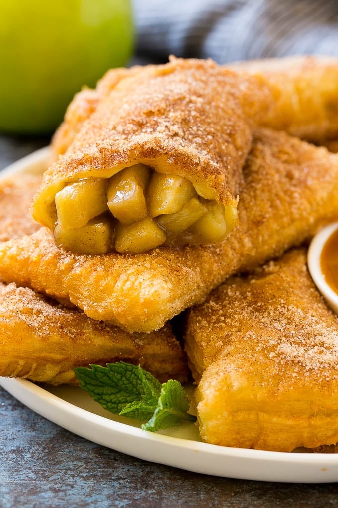Fried Apple Pies Recipe | McDonald's Copycat Recipe | Apple Pie | Apple Hand Pies #pie #apples #applepie #dessert #snack #ezlod Fried apple pies on a plate served with caramel sauce and topped with cinnamon sugar.