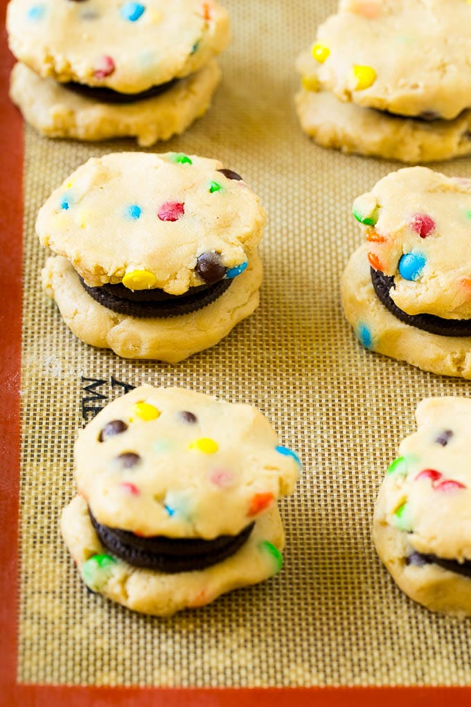 Oreo Stuffed Cookies Recipe | M&M's cookies | Stuffed Cookies #cookies #chocolate #oreos #dessert #baking #ezlod Cookie dough sandwiched around Oreos on a baking sheet.
