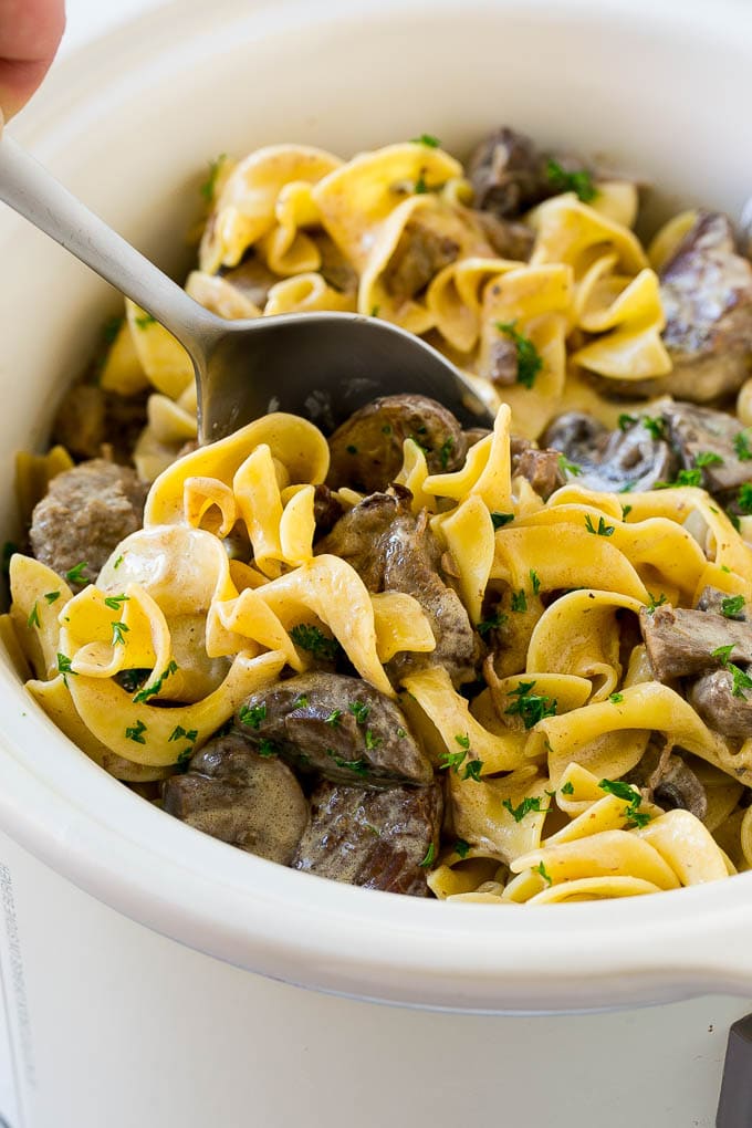 Slow Cooker Beef Stroganoff Recipe | Crock Pot Beef Stroganoff | Beef Recipe #slowcooker #crockpot #beef #mushrooms #pasta #dinner #ezlod A crock pot of beef stroganoff with a serving spoon in it.