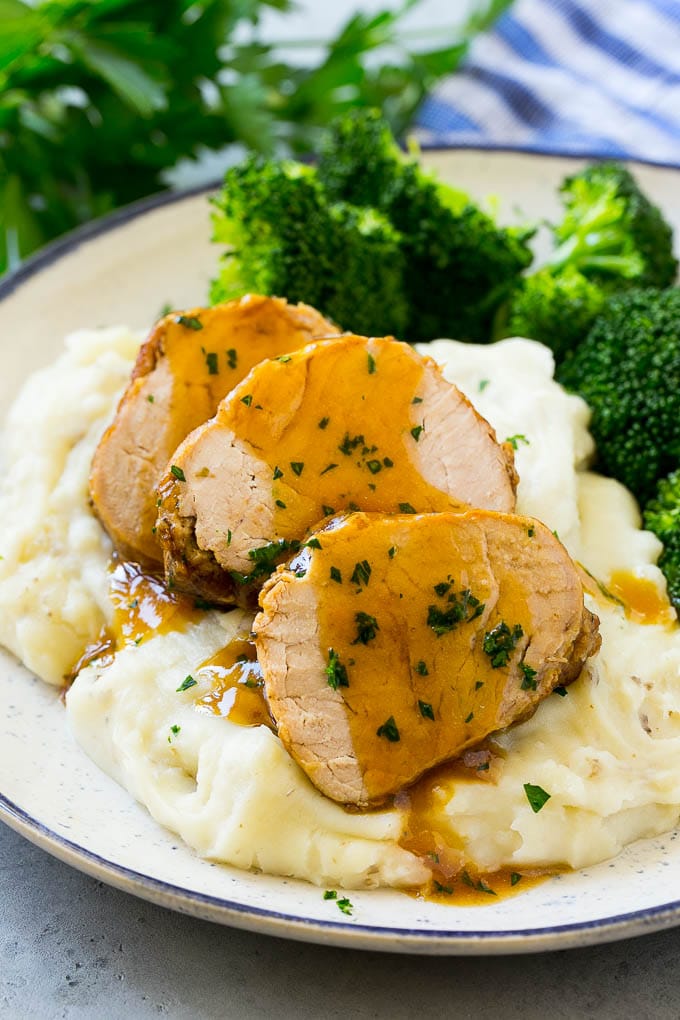 Slow Cooker Pork Tenderloin Recipe | Crock Pot Pork Tenderloin | Easy Pork Tenderloin #slowcooker #crockpot #pork #dinner #ezlod Sliced slow cooker pork tenderloin served over mashed potatoes with broccoli.