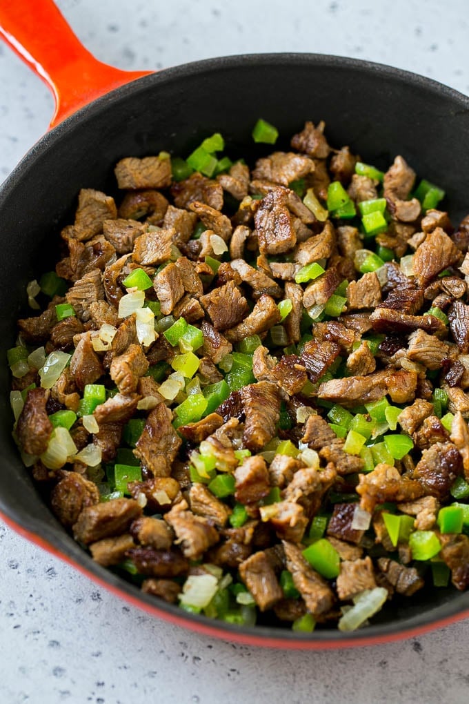 Philly Cheesesteak Dip Recipe | Cheesy Dip | Baked Cheese Dip #steak #dip #appetizer #cheese #ezlod Seared rib eye steak, peppers and onions in a pan.