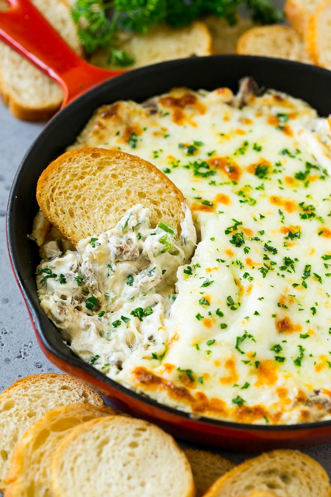 Philly Cheesesteak Dip Recipe | Cheesy Dip | Baked Cheese Dip #steak #dip #appetizer #cheese #ezlod Philly cheesesteak dip with a baguette piece scooping some dip out.