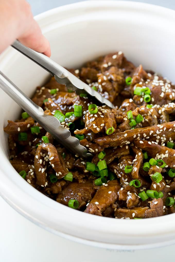 Slow Cooker Korean Beef Recipe | Korean Beef | Flank Steak Recipe #dinner #beef #slowcooker #crockpot #asian #ezlod A crock pot of Korean beef with serving tongs in it.