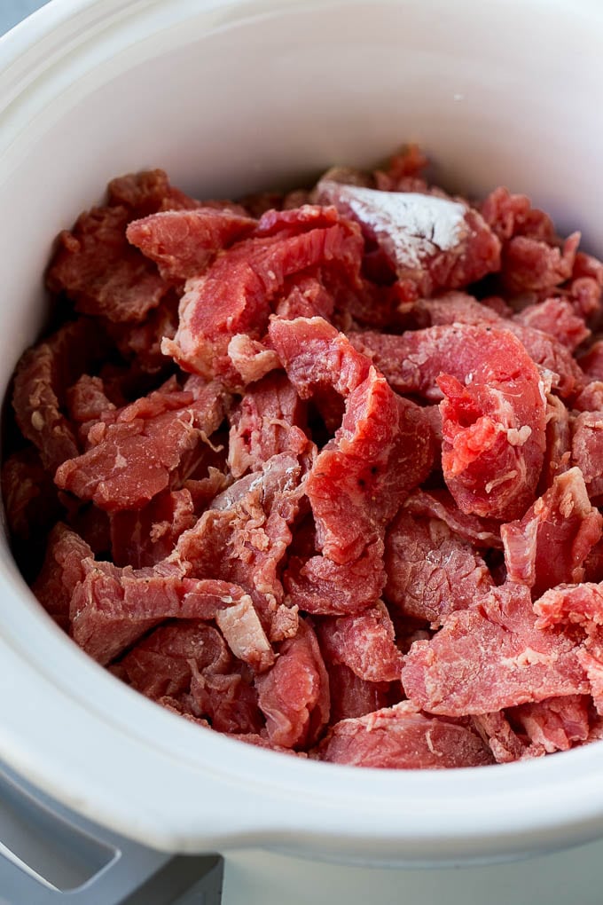 Slow Cooker Korean Beef Recipe | Korean Beef | Flank Steak Recipe #dinner #beef #slowcooker #crockpot #asian #ezlod Flank steak strips tossed in cornstarch inside a slow cooker.
