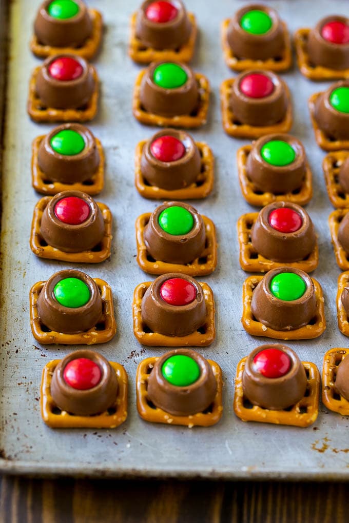Rolo Pretzels Recipe | Chocolate Pretzels | Caramel Pretzels | Holiday Candy #christmas #baking #dessert #candy #chocolate #caramel #pretzels #ezlod Treats with red and green M&M's pressed on top all on a baking sheet.