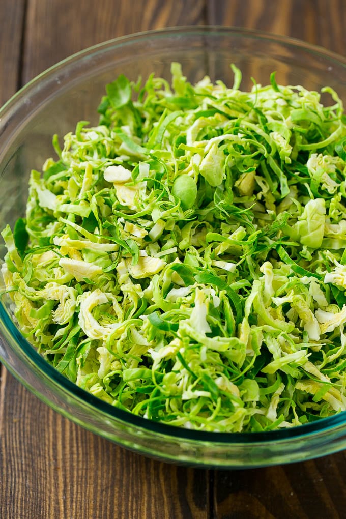 Brussels Sprout Salad Recipe | Shredded Brussels Sprouts Salad | Fall Salad #salad #brusselssprouts #bacon #thanksgiving #pomegranate #apple #dinner #ezlod Shredded sprouts in a glass bowl.