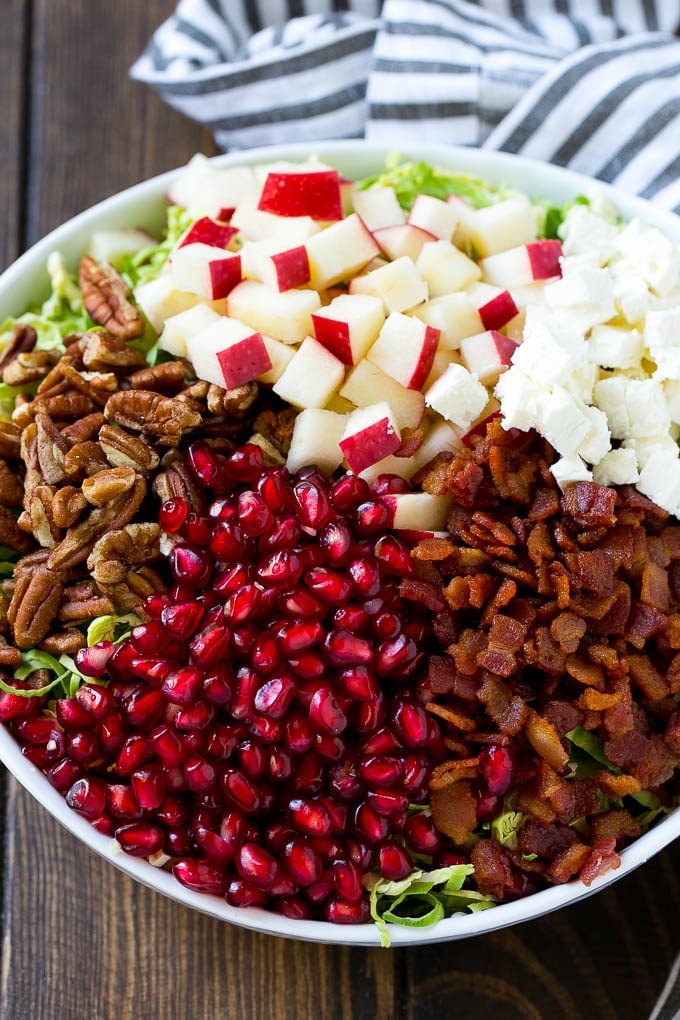 Brussels Sprout Salad Recipe | Shredded Brussels Sprouts Salad | Fall Salad #salad #brusselssprouts #bacon #thanksgiving #pomegranate #apple #dinner #ezlod Shredded brussels sprouts topped with pomegranate seeds, bacon, feta cheese and apples.
