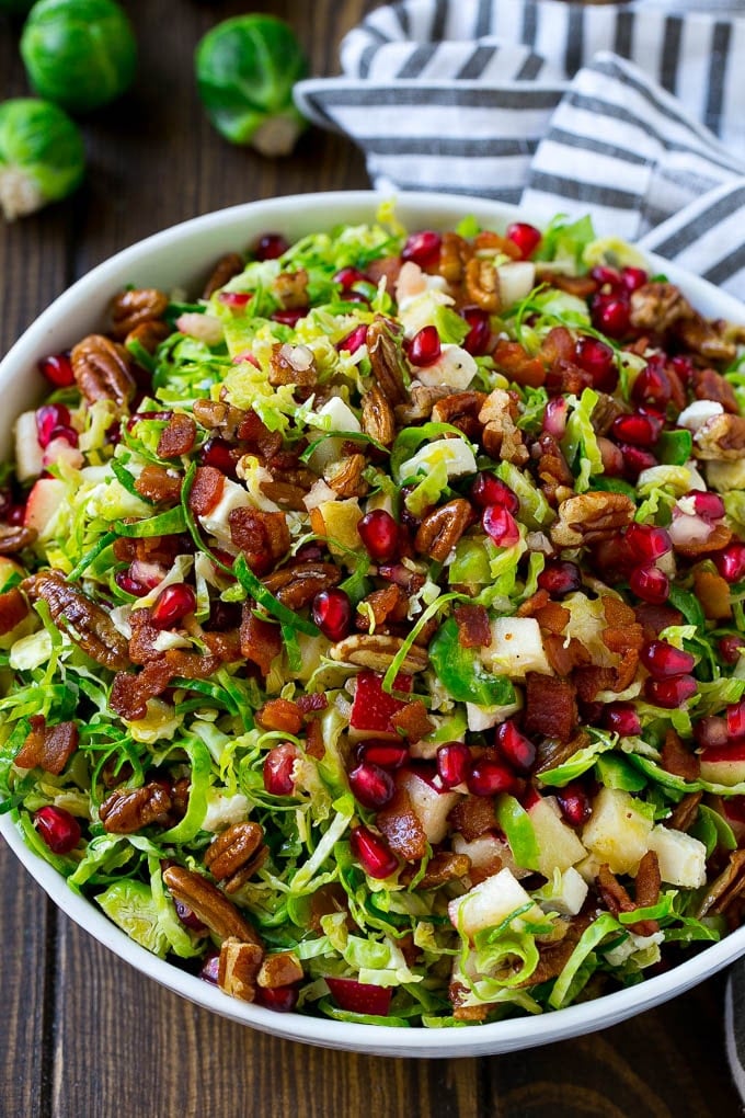 Brussels Sprout Salad Recipe | Shredded Brussels Sprouts Salad | Fall Salad #salad #brusselssprouts #bacon #thanksgiving #pomegranate #apple #dinner #ezlod A bowl of salad made with pomegranate, bacon and apples.