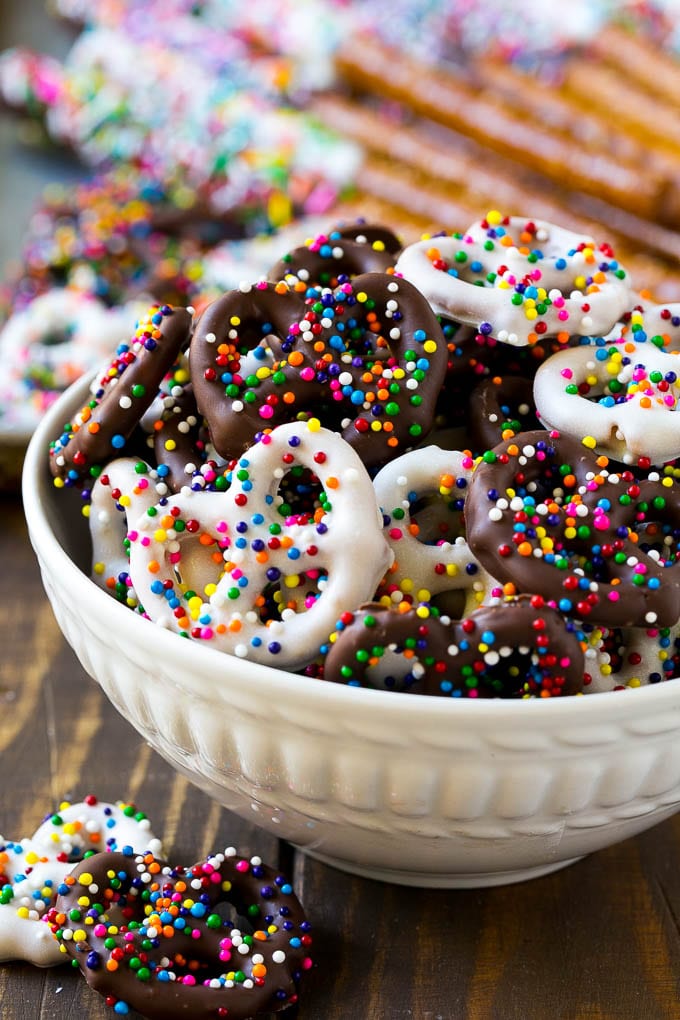 Chocolate Covered Pretzels Recipe | Sprinkle Pretzels | No Bake Dessert #pretzels #chocolate #christmas #sprinkles #candy #ezlod A bowl of chocolate covered pretzels decorated with rainbow sprinkles.