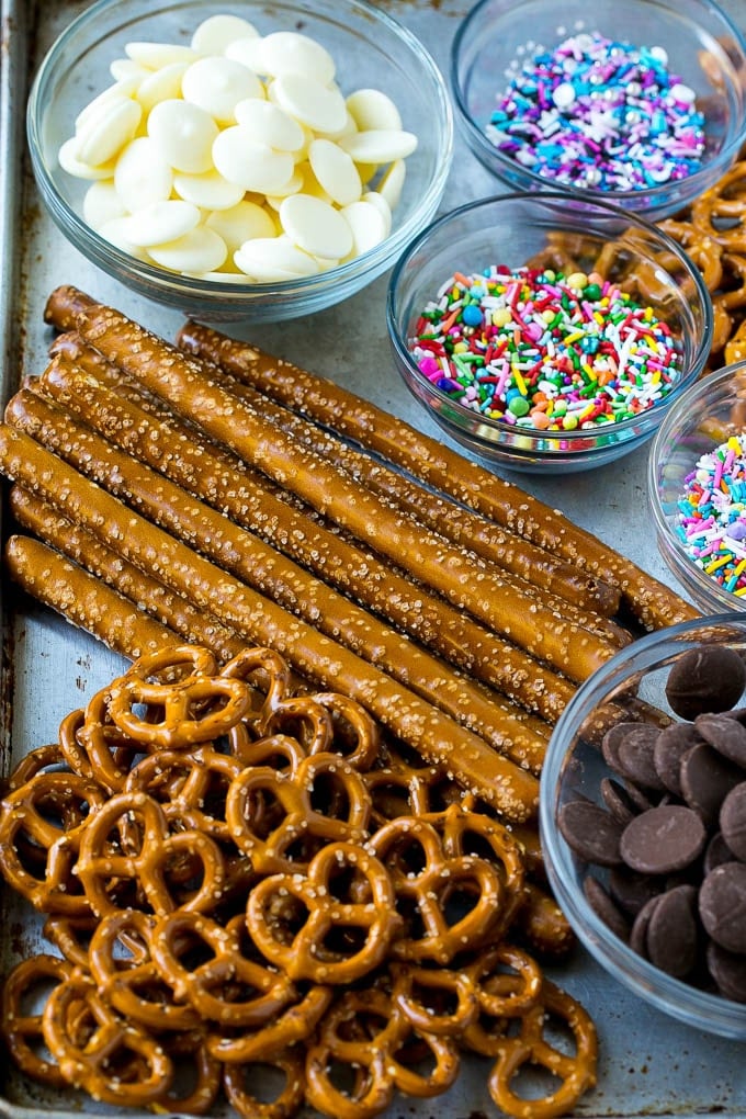 Chocolate Covered Pretzels Recipe | Sprinkle Pretzels | No Bake Dessert #pretzels #chocolate #christmas #sprinkles #candy #ezlod Ingredients including candy melts and sprinkles on a sheet pan.