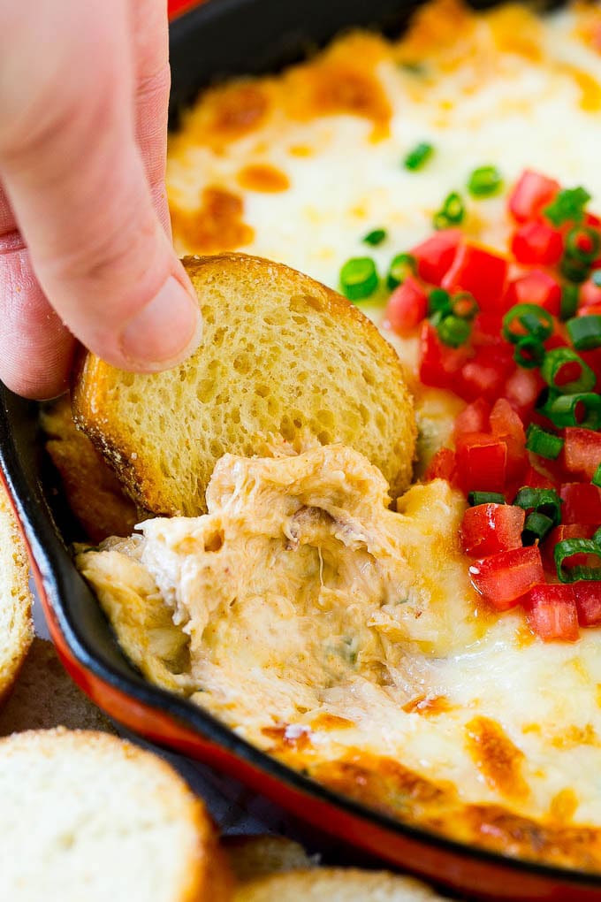Crab Dip Recipe | Hot Crab Dip | Seafood Dip #dip #crab #seafood #appetizer #ezlod #cheese A hand scooping out some crap dip with a crostini toast.