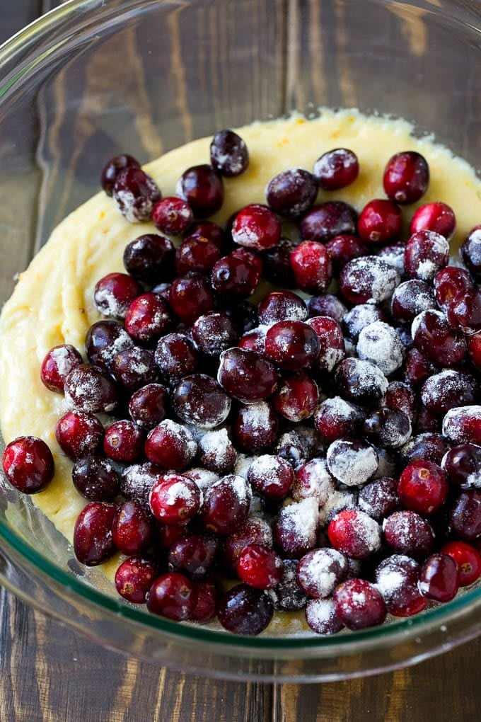 Cranberry Bread Recipe | Cranberry Loaf | Cranberry Orange Bread #cranberry #bread #baking #dessert #fall #ezlod Orange batter topped with a pile of fresh cranberries in a mixing bowl.