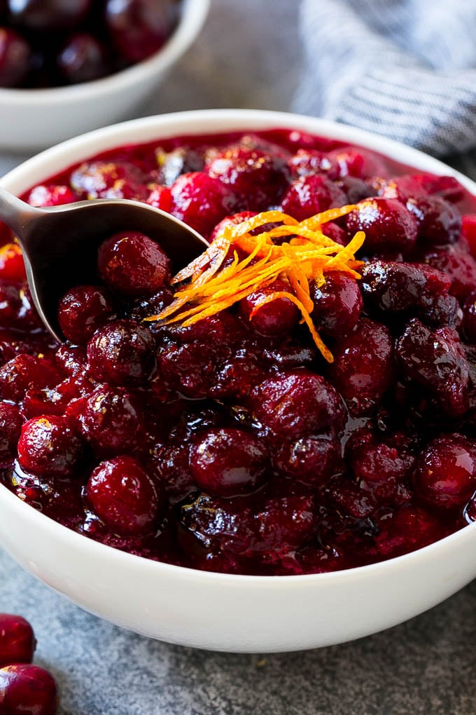 Cranberry Orange Sauce Recipe | Homemade Cranberry Sauce | Fresh Cranberry Sauce #cranberry #orange #fall #thanksgiving #sauce #dinner #ezlod A serving spoon in a bowl of cranberry orange sauce.