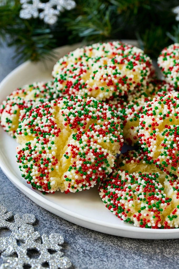 Gooey Butter Cookies Recipe | Cake Mix Cookies | Sprinkle Cookies | Christmas Cookies #cookies #butter #sprinkles #christmas #dessert #baking #ezlod A plate of gooey butter cookies covered in holiday sprinkles.