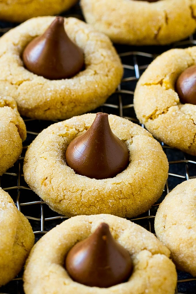 Peanut Butter Blossoms Recipe | Hershey Kiss Cookies | Chocolate Peanut Butter Cookies #cookies #peanutbutter #chocolate #dessert #baking #christmas #christmascookies #ezlod Peanut butter blossom cookies on a cooling rack.