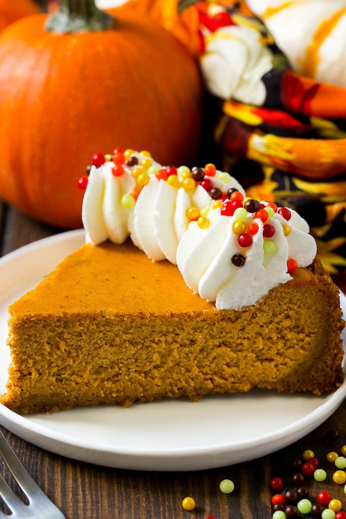 Pumpkin Cheesecake Recipe | Pumpkin Pie Cheesecake | Pumpkin Dessert #pumpkin #thanksgiving #dessert #cheesecake #fall #ezlod A slice of pumpkin cheesecake on a graham cracker crust, topped with whipped cream and sprinkles.