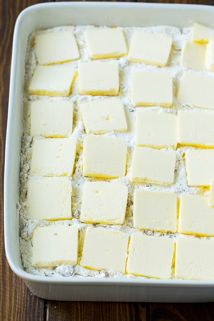 Pumpkin Dump Cake Recipe | Pumpkin Cake | Pumpkin Pie Cake #pumpkin #cake #pecans #fall #thanksgiving #dessert #ezlod Cake mix layered with sliced butter in a baking dish.