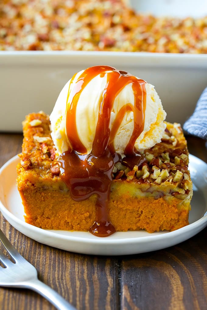 Pumpkin Dump Cake Recipe | Pumpkin Cake | Pumpkin Pie Cake #pumpkin #cake #pecans #fall #thanksgiving #dessert #ezlod A slice of pumpkin dump cake topped with ice cream and caramel sauce.