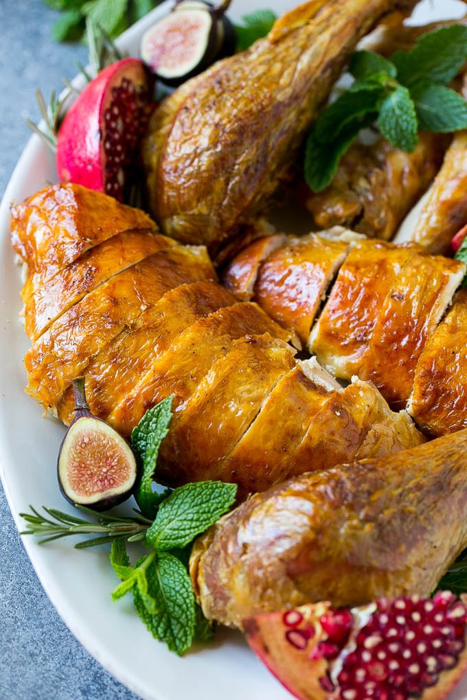 Roast Turkey Recipe | Thanksgiving Turkey | Holiday Turkey | Baked Turkey #turkey #thanksgiving #christmas #dinner #glutenfree #ezlod Sliced roast turkey on a serving platter with rosemary, pomegranate and figs.