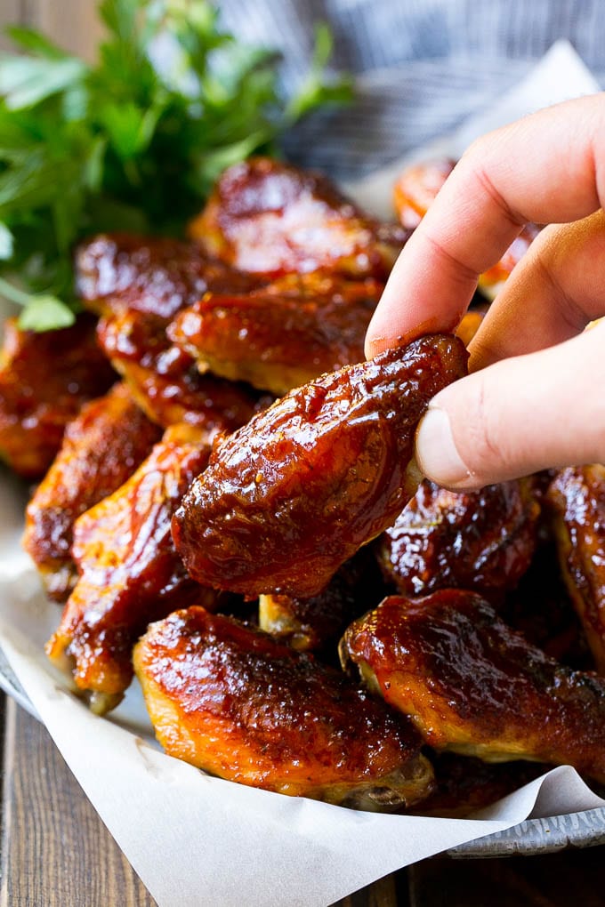 Smoked Chicken Wings | Barbecue Chicken Wings | BBQ Chicken Wings #chicken #wings #bbq #barbecue #appetizer #dinner #ezlod A pile of smoked chicken wings with a hand reaching out for one.