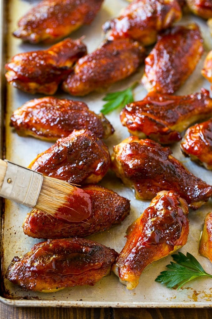 Smoked Chicken Wings | Barbecue Chicken Wings | BBQ Chicken Wings #chicken #wings #bbq #barbecue #appetizer #dinner #ezlod BBQ sauce brushed onto a sheet pan of smoked chicken wings.