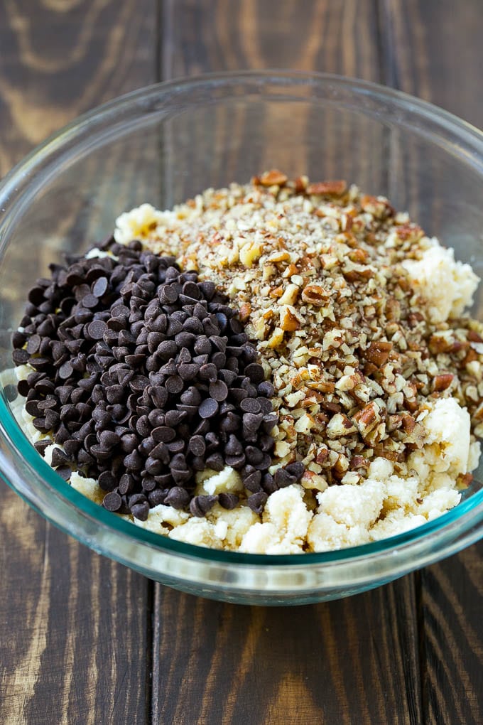 Snowball Cookies Recipe | Mexican Wedding Cookies | Russian Tea Cakes #cookies #pecan #chocolate #baking #dessert #christmas #ezlod A bowl of dough topped with miniature chocolate chips and chopped pecans.