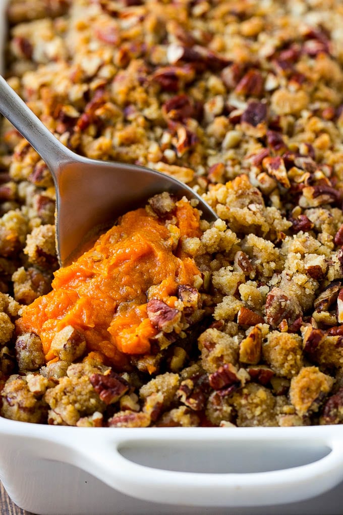 Sweet Potato Casserole with Pecans Recipe | Sweet Potato Casserole | Sweet Potato Side Dish #sweetpotatoes #thanksgiving #pecans #casserole #sidedish #holiday #fall #ezlod A dish of sweet potato casserole with pecans with a serving spoon in it.