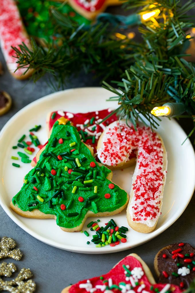 Christmas Sugar Cookies Recipe | Christmas Cookies #cookies #frosting #sprinkles #sugarcookies #christmas #dessert #ezlod A selection of Christmas sugar cookies served on a plate, with holiday decorations in the background.