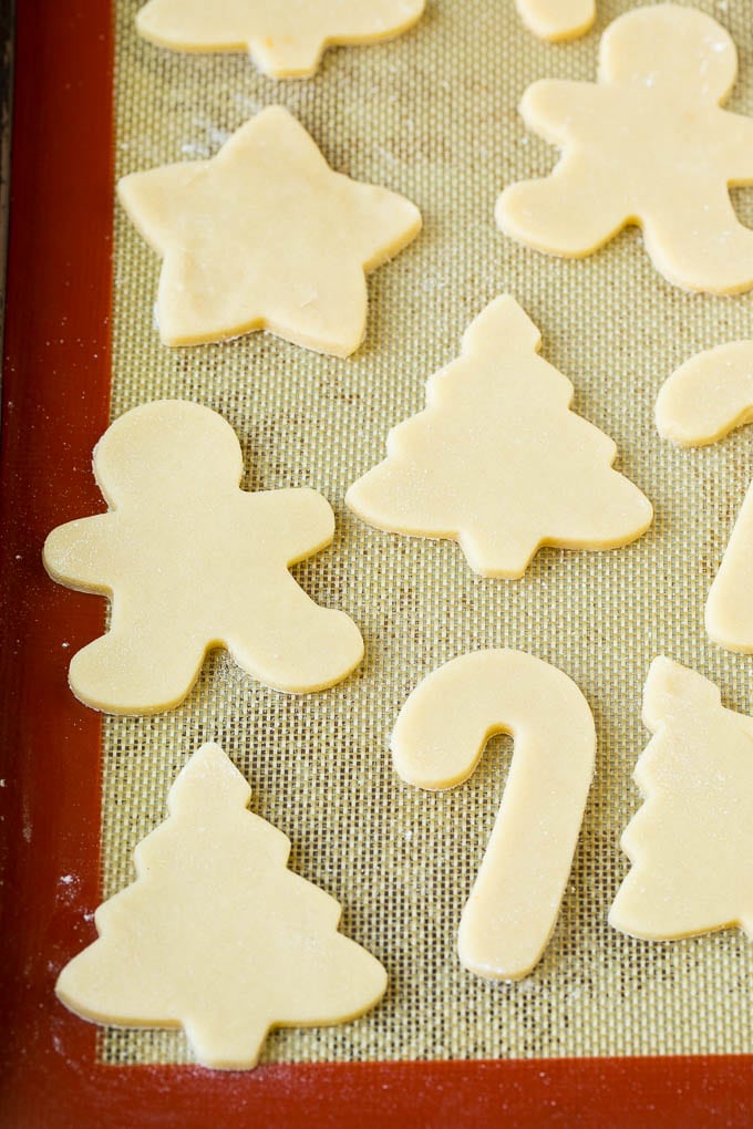 Christmas Sugar Cookies Recipe | Christmas Cookies #cookies #frosting #sprinkles #sugarcookies #christmas #dessert #ezlod Cookie dough cut into holiday shapes on a baking sheet.
