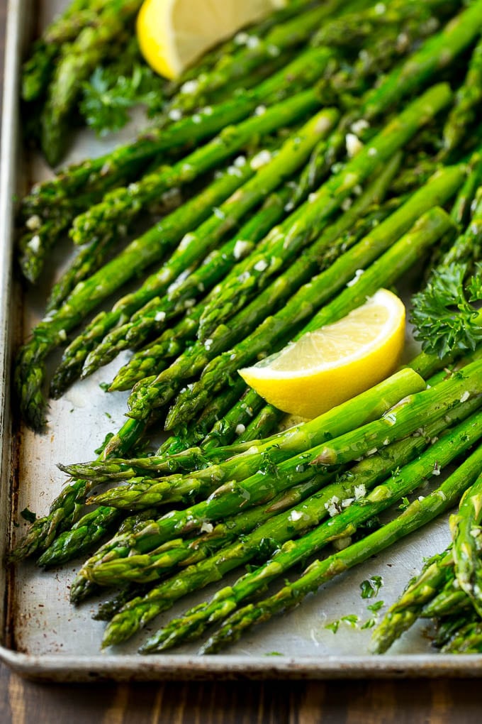 Roasted Asparagus Recipe | Baked Asparagus | Asparagus Side Dish #asparagus #garlic #sidedish #keto #lowcarb #dinner #ezlod Roasted asparagus on a sheet pan, topped with chopped parsley and garnished with lemon wedges.