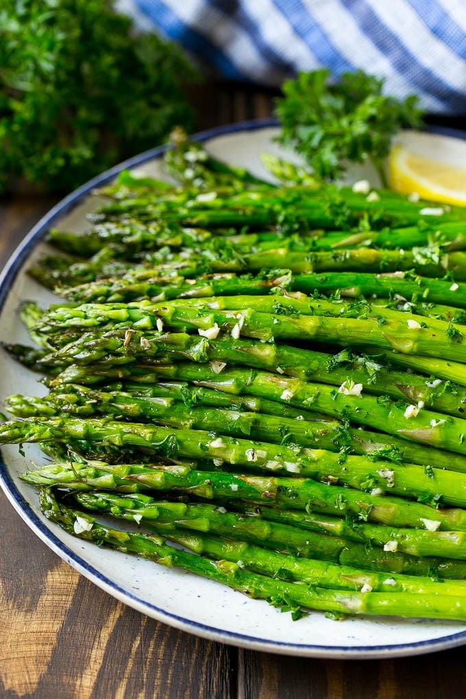 Roasted Asparagus Recipe | Baked Asparagus | Asparagus Side Dish #asparagus #garlic #sidedish #keto #lowcarb #dinner #ezlod A serving plate of roasted asparagus topped with chopped parsley.