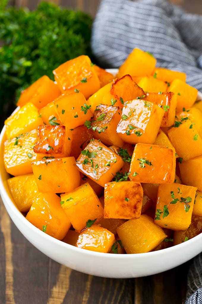 Roasted Butternut Squash Recipe | Baked Butternut Squash | Butternut Squash Side Dish #butternutsquash #squash #fall #vegetarian #dinner #ezlod A bowl of roasted butternut squash made with brown sugar and maple syrup, then garnished with chopped parsley.