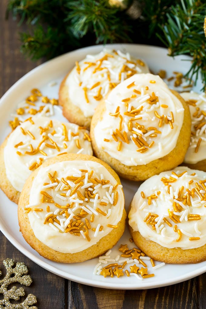 Eggnog Cookies Recipe | Holiday Cookies | Christmas Cookies #cookies #eggnog #baking #christmas #sprinkles #dessert #ezlod Eggnog cookies topped with frosting and gold sprinkles on a serving plate.