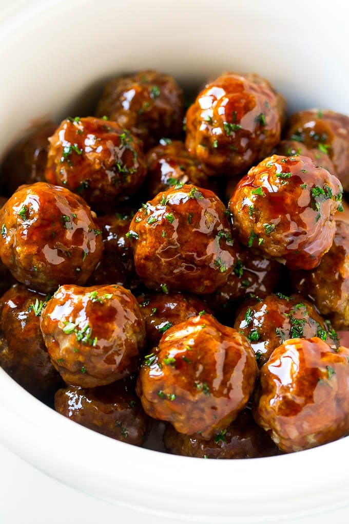 Sweet and Sour Meatballs Recipe | Slow Cooker Meatballs | Crockpot Meatballs | Cocktail Meatballs #meatballs #beef #slowcooker #crockpot #dinner #appetizer #ezlod Sweet and sour meatballs garnished with parsley in a slow cooker.