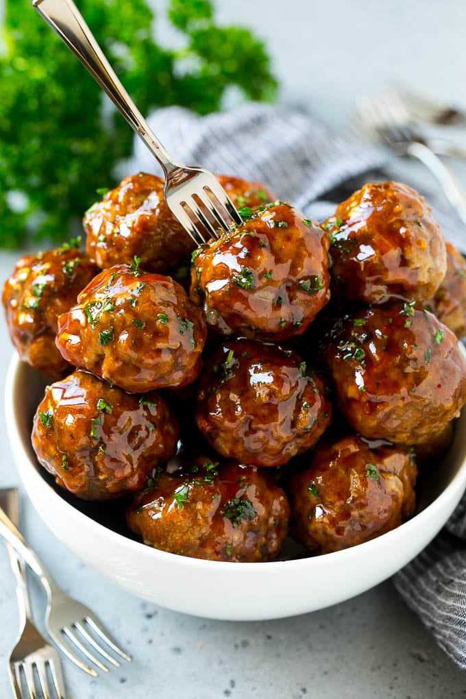 Sweet and Sour Meatballs Recipe | Slow Cooker Meatballs | Crockpot Meatballs | Cocktail Meatballs #meatballs #beef #slowcooker #crockpot #dinner #appetizer #ezlod A bowl of sweet and sour meatballs with a cocktail fork in it.