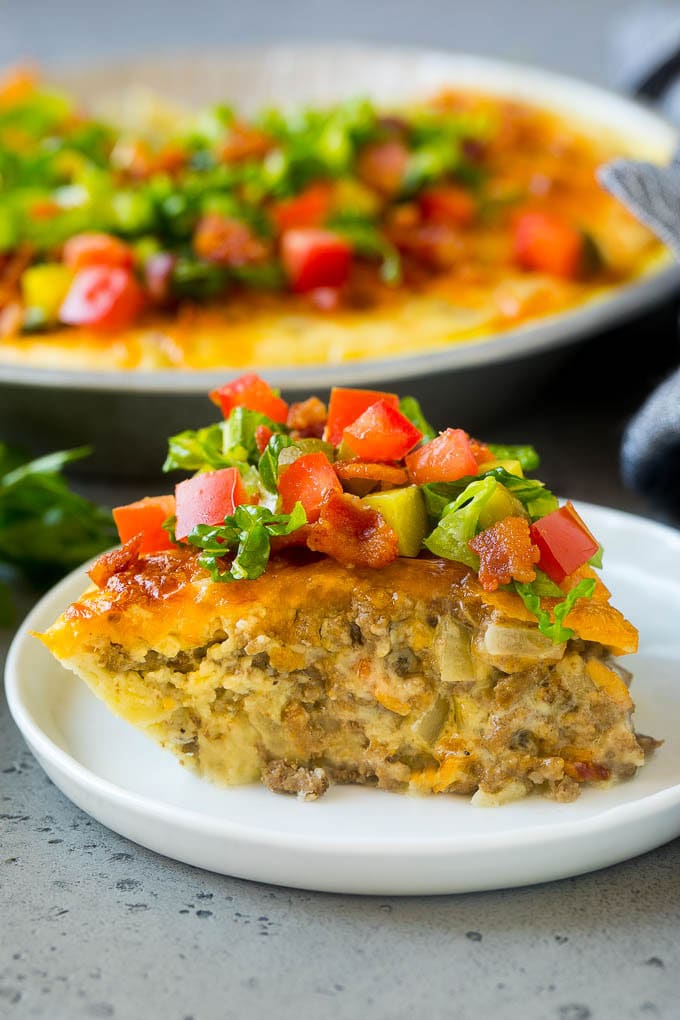 Cheeseburger Pie Recipe | Cheeseburger Casserole | Ground Beef Recipe #cheeseburger #beef #bacon #cheese #casserole #dinner #ezlod A slice of cheeseburger pie garnished with shredded lettuce, diced tomatoes and pickles.