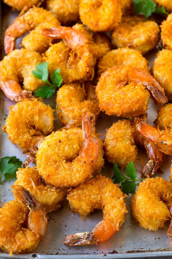 Coconut Shrimp Recipe | Fried Shrimp | Shrimp Appetizer #shrimp #coconut #appetizer #seafood #dinner #ezlod A pile of crispy coconut shrimp on a sheet pan with cilantro leaves for garnish.